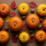 Top-down flatlay of assorted pumpkins, colorful autumn leaves, and acorns on a rustic wooden surface.