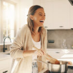 Happy Woman Cooking Healthy Meal Home Kitchen Lifestyle, bright and cheerful, culinary blog use, transparent background PNG.